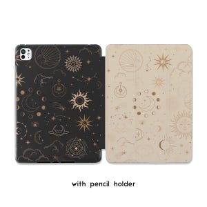 Könnte beinhalten: Schwarze und beige Tablet-Hülle mit Himmelsmustern. Die schwarze Hülle zeigt goldene Sonnen, Monde, Sterne und Sternbilder. Die beige Hülle hat ähnliche goldene Himmelsmuster. Der Text "with pencil holder" steht unten.