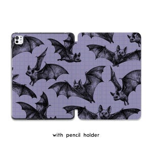 May include: A tablet case featuring a repeating pattern of detailed black bat illustrations on a light purple background. The case is open, revealing the interior. The text "with pencil holder" is at the bottom.