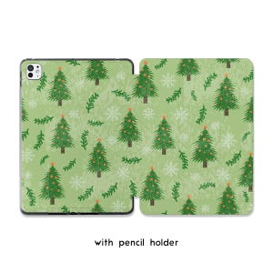 May include: Green tablet case with a Christmas tree pattern. The design features green Christmas trees with orange star toppers, white snowflakes, and green sprigs on a light green background. The text "with pencil holder" is at the bottom.