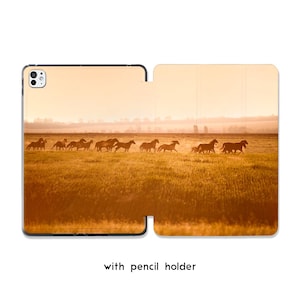 Può includere: Una custodia per iPad con un'immagine di un branco di cavalli che corrono attraverso un campo dorato sotto un cielo caldo e nebbioso. La custodia ha un portapenne e una protezione.