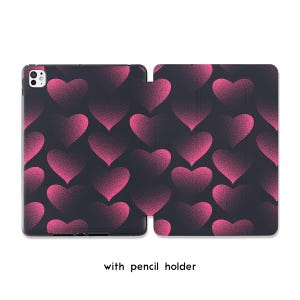 May include: A tablet case with a dark background and a pattern of pink hearts. The hearts have a gradient effect, with a lighter pink in the center and a darker pink outline. The text "with pencil holder" is at the bottom.