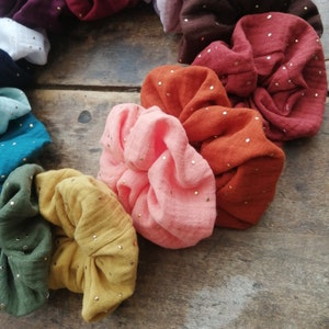 May include: A set of colorful hair scrunchies with gold glitter. The scrunchies are made of soft fabric and are perfect for adding a touch of style to any outfit.
