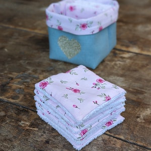 Lot de 12 lingettes format 8 x 8 cm en microfibre et coton imprimé roses sur fond rose pâle. Elles sont rangées dans un panier en lin vert sauge avec un coeur pailleté .  Il mesure 9 cm de côté environ.