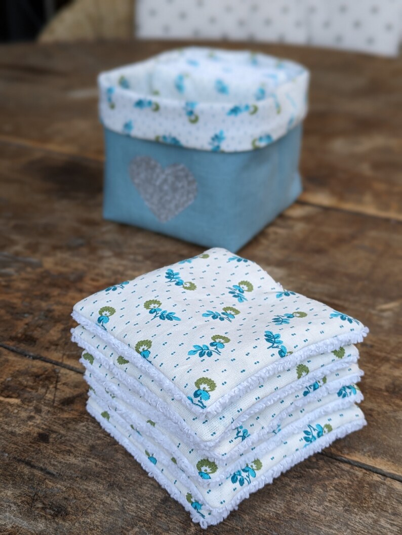 Lot de 12 lingettes format 8 x 8 cm en microfibre et coton imprimé fleurs vertes sur fond écru. Elles sont rangées dans un panier en lin vert avec un coeur pailleté .  Il mesure 9 cm de côté environ.