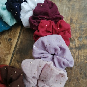 May include: A set of ten colorful scrunchies with gold glitter dots. The scrunchies are made of soft fabric and are perfect for holding hair in place.