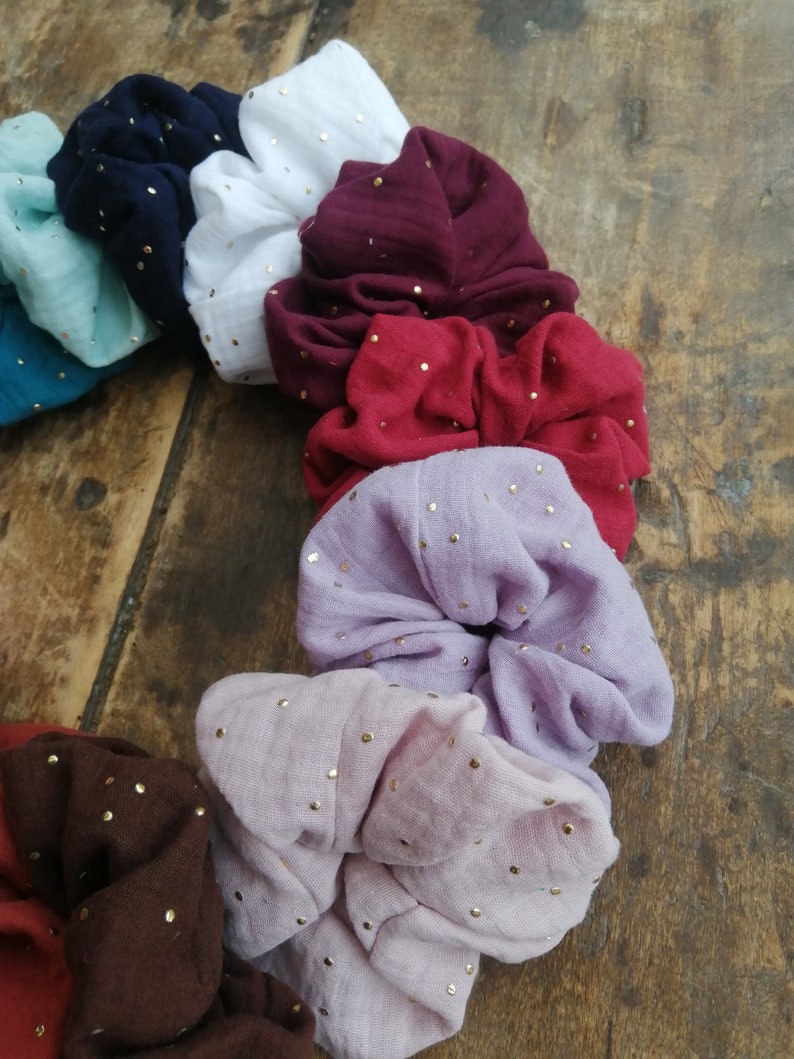 May include: A set of ten colorful scrunchies with gold glitter dots. The scrunchies are made of soft fabric and are perfect for holding hair in place.