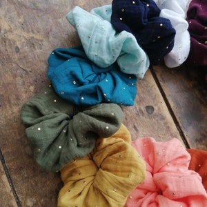 May include: A set of colorful scrunchies with gold glitter. The scrunchies are made of soft fabric and are perfect for adding a touch of style to any outfit.