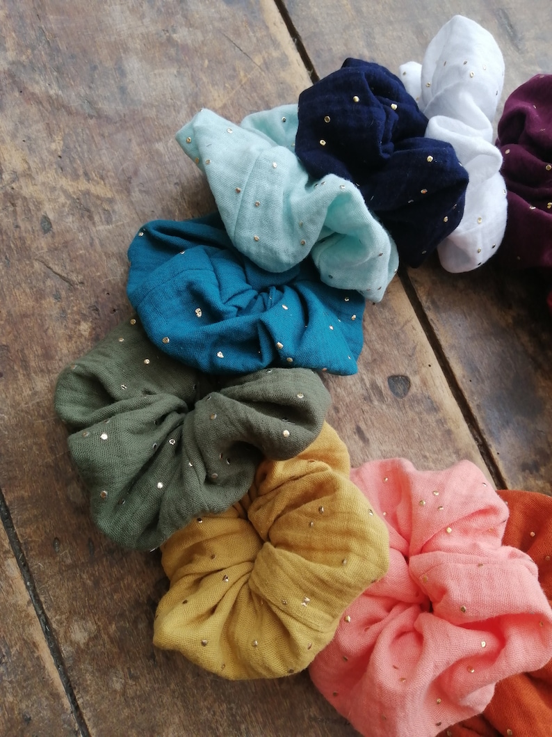 May include: A set of colorful scrunchies with gold glitter. The scrunchies are made of soft fabric and are perfect for adding a touch of style to any outfit.