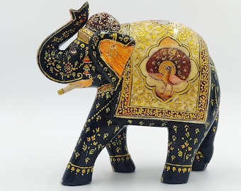 Könnte beinhalten: Handbemalte Holz-Elefantenfigur in Schwarz, Gold und Creme. Der Elefant hat aufwendige Blumen- und Pfauenfedermuster. Der Rüssel ist erhoben und die Ohren sind orange. Ein dekoratives Stück für die Inneneinrichtung.