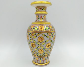 Könnte beinhalten: Eine dekorative Marmorvase mit floralem Design. Die Vase hat einen hellgrauen Hintergrund mit gelben Blumen und grünen Blättern. Goldene Verzierungen akzentuieren die Oberseite, den Boden und den Hals. Die Vase ist etwa 25 cm hoch.