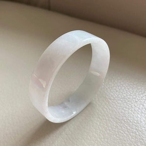 May include: A white jade bangle bracelet. The bracelet is smooth and polished, with a subtle sheen.