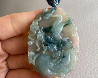 May include: A jade pendant with a detailed carving of a dragon, set on a blue cord.