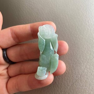 May include: A green jade carving of a mythical creature, possibly a dragon or a phoenix. The carving is detailed and intricate, with a smooth, polished finish.