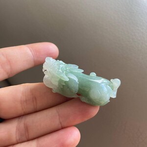 May include: A green jade carving of a mythical creature, possibly a dragon or a lion, with intricate details. The carving is smooth and polished, and the jade has a translucent quality.
