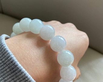 May include: A white jadeite bracelet with round beads. The bracelet is made of natural jade and has a smooth, polished finish.
