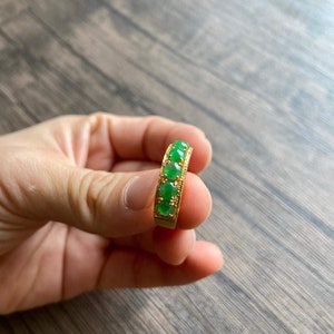 May include: A gold ring with five green jade stones set in a band.