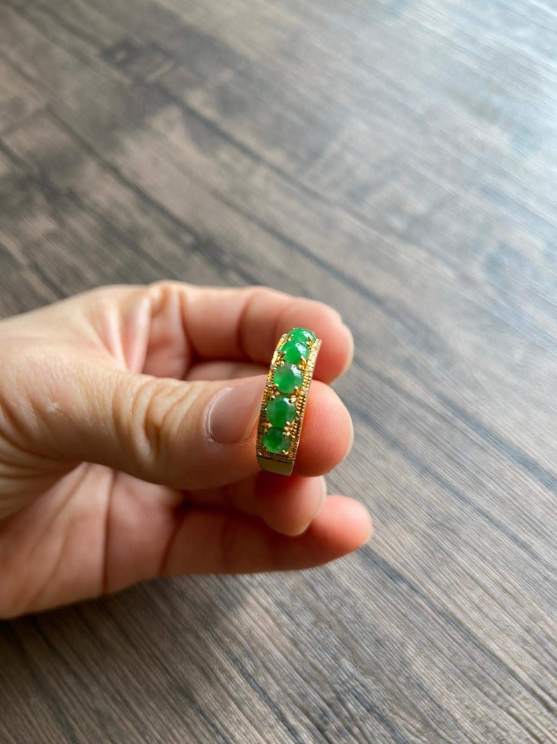 May include: A gold ring with five green jade stones set in a band.