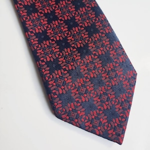 Late 1970s vintage tie in a textured ornate pattern in red on a navy blue background. Original 70s necktie by St. Michael.