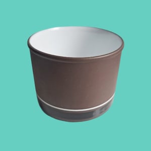 May include: A brown ceramic cup with a white interior and a thin white band around the top. The cup has a dark brown band around the bottom.