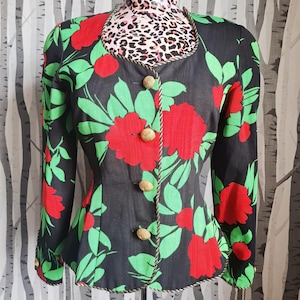 May include: A black floral blazer with red flowers and green leaves. The blazer has gold buttons and a decorative rope trim. The collar is trimmed with a rope design. The blazer is a vintage style.