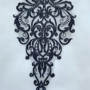 Könnte beinhalten: Schwarze Spitzenapplikation mit einem zarten Blumenmuster. Die Applikation ist perfekt, um Kleidung, Accessoires oder Wohnaccessoires einen Hauch von Eleganz zu verleihen.