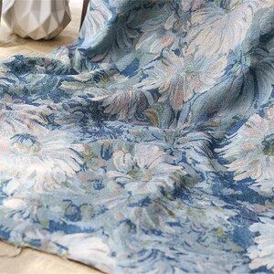 May include: A blue fabric with a white floral pattern. The fabric has a textured surface and a slightly faded look.