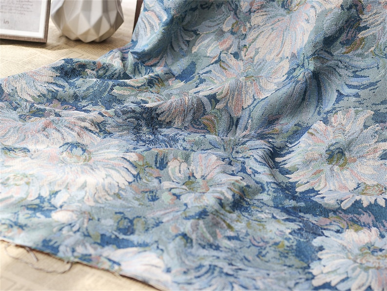 May include: A blue fabric with a white floral pattern. The fabric has a textured surface and a slightly faded look.