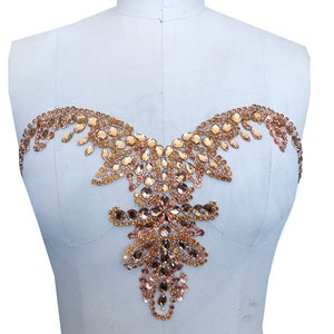 May include: A gold-toned beaded embellishment with a teardrop shape. The embellishment is made of small, faceted beads that are sewn together in a decorative pattern.