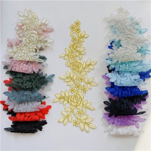 May include: Assortment of lace appliques in various colors, including pink, blue, green, red, black, and gold. The appliques feature floral designs with intricate details.