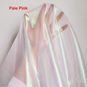 May include: Pale pink iridescent sheer fabric with a subtle shimmer. The fabric is translucent and has a soft, flowing texture.