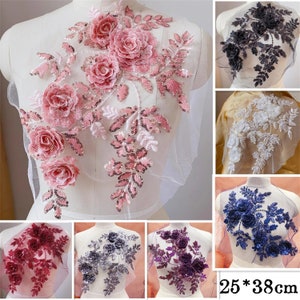 Può includere: Assortimento di applicazioni floreali in vari colori, tra cui rosa, bianco, blu, viola e grigio. Ogni applicazione presenta intricati disegni floreali con paillettes e perline. Le applicazioni sono di circa 25 per 38 centimetri.