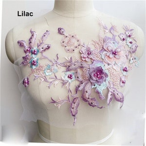 May include: Lilac floral applique with pearl accents. The applique features a variety of flowers and leaves in shades of purple, pink, and blue. The applique is perfect for adding a touch of elegance to any garment or project.