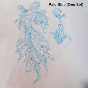 Peut inclure: Ensemble d'appliques de poissons à paillettes bleu pâle. L'ensemble comprend deux appliques de poissons, une grande et une petite, avec des détails de paillettes complexes. Les appliques sont bleu pâle avec des paillettes irisées. Le texte "Pale Blue (One Set)" est visible.