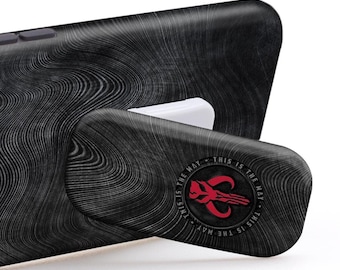 May include: Black phone case with a textured design and a pop-out stand. The stand has a Mandalorian symbol and the text "This is the way." 