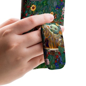 May include: A phone case with a colorful floral design featuring sunflowers and a character from the Star Wars franchise. The case has a pop socket attached to the back, featuring the same character.