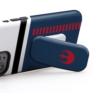 May include: A smartphone case in white, navy blue, and black with a red graphic and the text "USE IT IN LANDSCAPE MODE TO WATCH VIDEOS". The case is propped up by a matching stand.