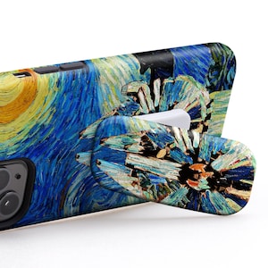 Pode incluir: Uma capa de telefone preta com um design de pintura de A Noite Estrelada. A capa tem um suporte de anel retrátil que também é decorado com a pintura A Noite Estrelada. O texto "USE IT IN LANDSCAPE MODE TO WATCH VIDEOS" é exibido acima da capa do telefone.