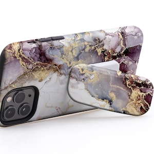 May include: A smartphone case with a marble design in shades of purple, gold, and white. The case is propped up by a built-in stand. The text on the image reads: USE IT IN LANDSCAPE MODE TO WATCH VIDEOS.