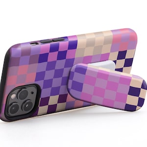 Può includere: Una custodia per telefono a scacchi viola, rosa e beige con un piedistallo. Il piedistallo è anche a scacchi ed è in posizione orizzontale. Il testo "USE IT IN LANDSCAPE MODE TO WATCH VIDEOS" è sopra la custodia del telefono.