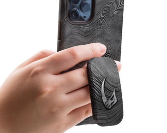 May include: A black and white phone case with a wavy pattern and a matching phone grip with a Mandalorian symbol. The case and grip are shown in a hand.