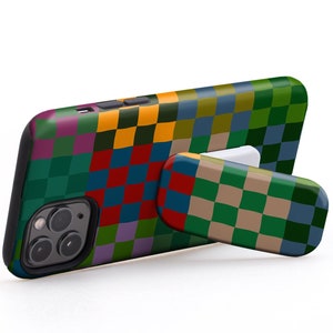 Può includere: Una custodia per telefono a quadri colorati con un piedistallo integrato. La custodia è progettata per tenere un telefono in modalità orizzontale per guardare i video. "USE IT IN LANDSCAPE MODE TO WATCH VIDEOS" è scritto in bianco su sfondo bianco.