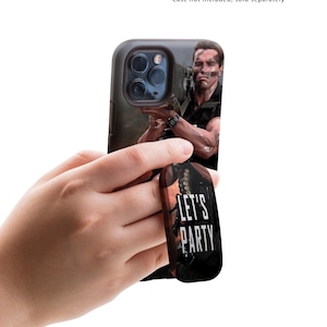May include: A black phone case with a picture of Arnold Schwarzenegger on it. The case has a black phone grip attached to the back with the text "LET'S PARTY" on it.