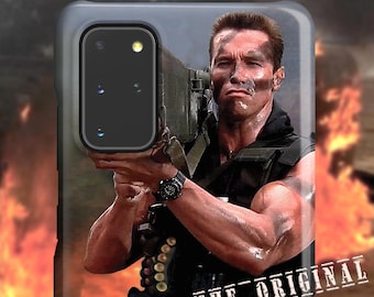 May include: A phone case featuring a movie still of a man holding a weapon, with a background of flames. The man has a determined expression and is wearing a black vest and a watch. The text "THE ORIGINAL" is printed on the bottom right.