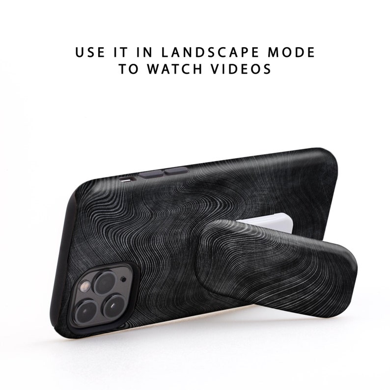 May include: Black phone case with a wood grain pattern and a built-in kickstand. The kickstand is extended and the phone is in landscape mode. "USE IT IN LANDSCAPE MODE TO WATCH VIDEOS" is written in white text on a white background.