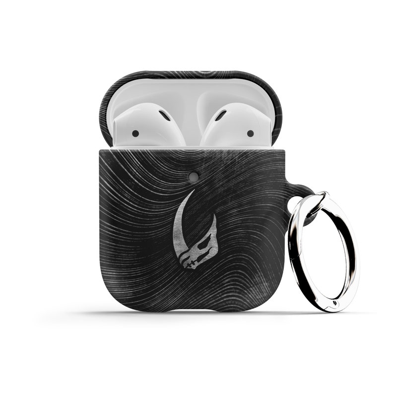 May include: Black and white patterned Airpods case with a silver Mandalorian symbol and a silver keychain ring.