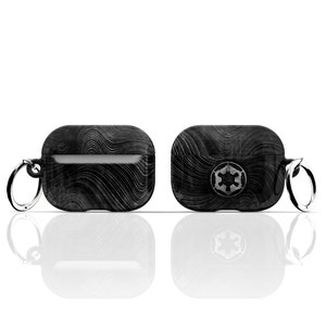 May include: Black and white patterned Airpods case with a silver keychain and a silver Imperial symbol on the front.