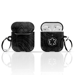 May include: Black and white patterned AirPod case with a silver key chain and the Imperial symbol from Star Wars.