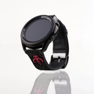 Op de afbeelding: Zwarte smartwatch met een rood en zwart Mandalorian-symbool op de band. Het horloge heeft een zwart wijzerplaat met witte markeringen.