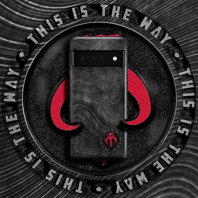 May include: A black phone case with a textured design and a Mandalorian symbol. The case has the text "This is the way" repeated around the edge.