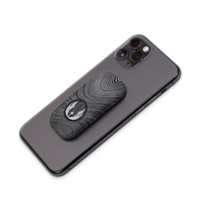 Pu&ograve; includere: Un telefono nero con un'impugnatura per telefono con il logo della Ribellione. L'impugnatura ha un motivo a venature del legno e un logo della Ribellione argentato.